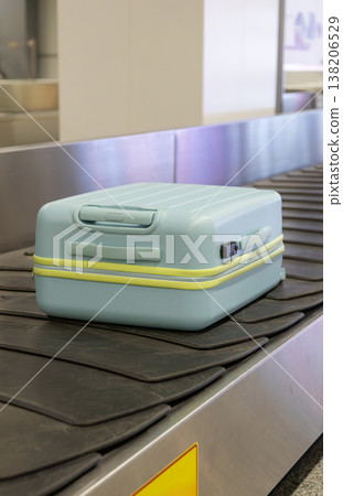 Light blue suitcase moving on airport baggage carousel with metal conveyor system terminal interior. Light blue suitcase moving on airport baggage carousel with metal conveyor system terminal interior. 138206529