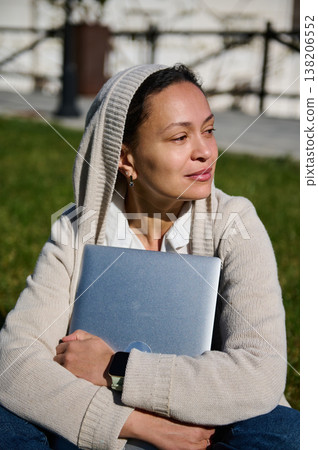 Woman Holding Laptop Outdoors Relaxing in Park Hoodie Remote Work Student Studying Technology Woman Holding Laptop Outdoors Relaxing in Park Hoodie Remote Work Student Studying Technology 138206552