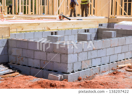 Construction workers build block wall foundation for new house in residential area Construction workers build block wall foundation for new house in residential area 138207422