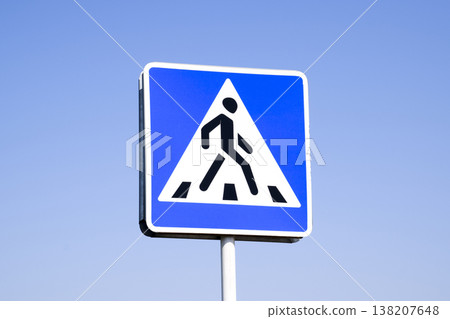 A pedestrian crossing sign. Sign on a blue sky background. A pedestrian crossing sign. Sign on a blue sky background. 138207648