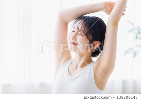 A young woman stretching in her bedroom in the morning. 138208143