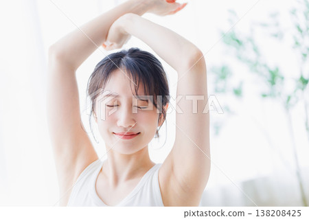 A young woman stretching in her bedroom in the morning. 138208425