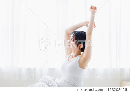 A young woman stretching in her bedroom in the morning. A young woman stretching in her bedroom in the morning. 138208426