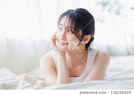 A young woman relaxing in bed A young woman relaxing in bed 138208429