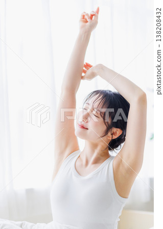A young woman stretching in her bedroom in the morning. A young woman stretching in her bedroom in the morning. 138208432