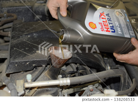 Oil change in the engine of the car. Filling the oil through the funnel. Car maintenance station. 138208533