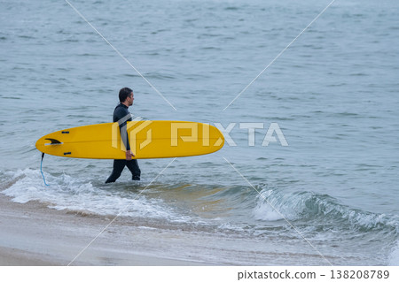 Surfer with board under his arm Surfer with board under his arm 138208789