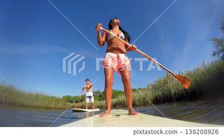 Woman stand up paddleboarding Woman stand up paddleboarding 138208926