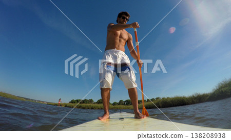 Man stand up paddleboarding 138208938