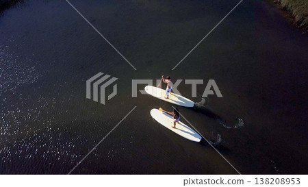 Man and woman stand up paddleboarding 138208953