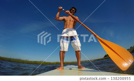Man stand up paddleboarding 138208955