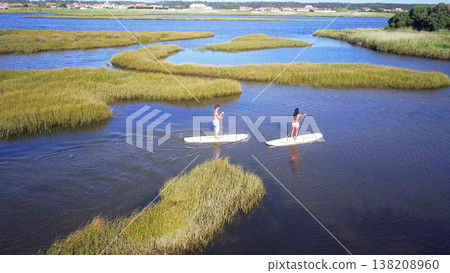 Man and woman stand up paddleboarding 138208960
