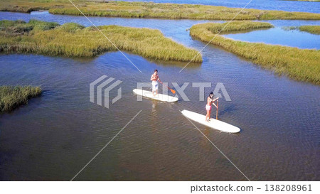 Man and woman stand up paddleboarding Man and woman stand up paddleboarding 138208961