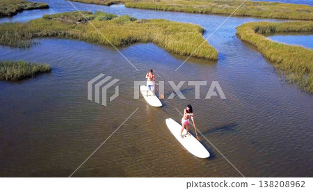 Man and woman stand up paddleboarding Man and woman stand up paddleboarding 138208962