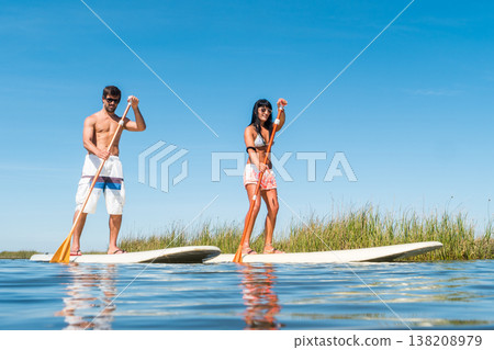 Man and woman stand up paddleboarding 138208979