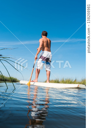 Man stand up paddleboarding 138208981