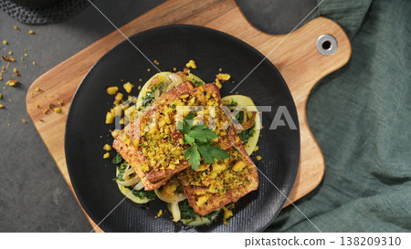 Crispy Tofu Steak with Sauteed Greens and Crumbled Topping on a Black Plate 138209310