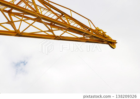 Yellow construction crane boom extending into a cloudy sky with large copy space. Yellow construction crane boom extending into a cloudy sky with large copy space. 138209326