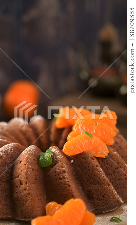 Close-up of a Golden Bundt Cake with Fresh Tangerine Slices and Mint 138209333