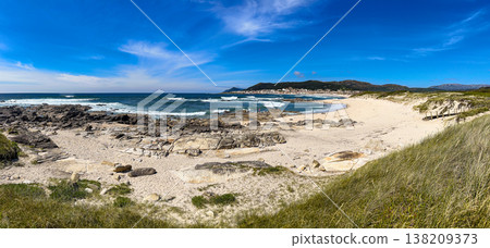 Panoramic view of Praia do Forte do Cao beach in Portugal with rocky shoreline and blue sky 138209373