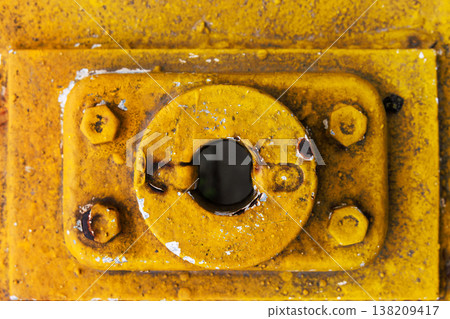 Close up of a yellow painted metal latch plate with bolts, rust, and dirt around an opening. industrial grunge texture background Close up of a yellow painted metal latch plate with bolts, rust, and dirt around an opening. industrial grunge texture background 138209417