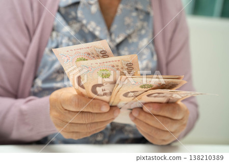 Retired elderly woman counting coins money and worry about monthly expenses and treatment fee payment. Retired elderly woman counting coins money and worry about monthly expenses and treatment fee payment. 138210389