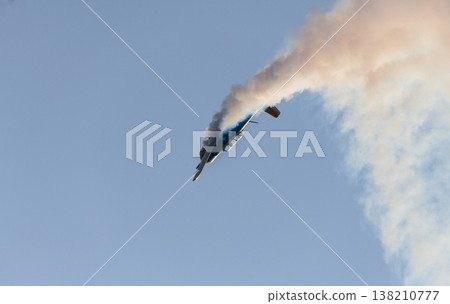 Aerobatic propeller airplane performing a steep maneuver while releasing a trail of smoke across a clear blue sky. 138210777