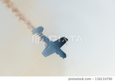 Aerobatic propeller airplane performing an air stunt while releasing a trail of smoke across a clear sky. Aerobatic propeller airplane performing an air stunt while releasing a trail of smoke across a clear sky. 138210780