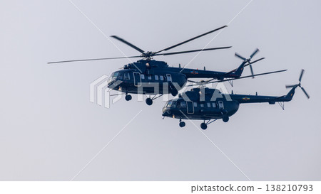 Two helicopters flying in close formation against a clear sky background. Coordinated aerial aviation transport and rotorcraft flight show Two helicopters flying in close formation against a clear sky background. Coordinated aerial aviation transport and rotorcraft flight show 138210793