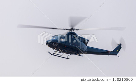 Helicopter flying with motion-blurred rotor blades against a clean sky background during an aerial demonstration at an airshow. Dynamic aviation scene with a sense of movement Helicopter flying with motion-blurred rotor blades against a clean sky background during an aerial demonstration at an airshow. Dynamic aviation scene with a sense of movement 138210800
