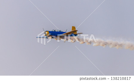 Aircraft performing an aerobatic maneuver with a smoke trail against a clear sky during an aerial aviation display Aircraft performing an aerobatic maneuver with a smoke trail against a clear sky during an aerial aviation display 138210817