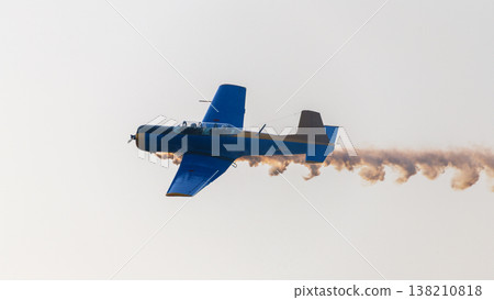 Aircraft performing an aerobatic maneuver with a smoke trail against a clear sky during an aerial aviation display Aircraft performing an aerobatic maneuver with a smoke trail against a clear sky during an aerial aviation display 138210818