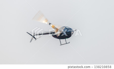Helicopter flying with motion-blurred rotor blades against a clean sky background during an aerial demonstration at an airshow. Dynamic aviation scene with a sense of movement Helicopter flying with motion-blurred rotor blades against a clean sky background during an aerial demonstration at an airshow. Dynamic aviation scene with a sense of movement 138210858