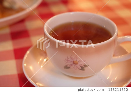 Tea served in a floral cup on a red checkered tablecloth, creating a café-like atmosphere. 138211850