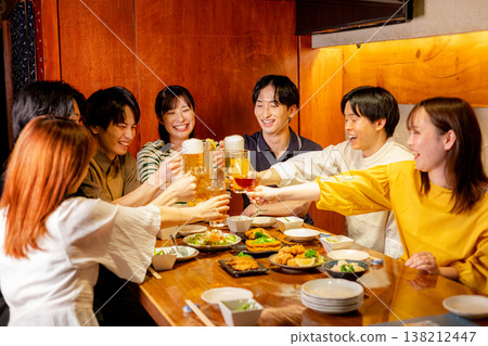 A young man and woman toast at an izakaya (Japanese pub). A young man and woman toast at an izakaya (Japanese pub). 138212447