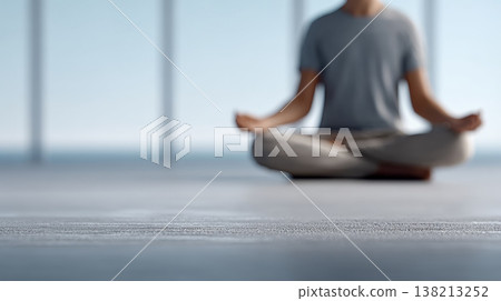 Blurred figure meditating in lotus position on a concrete floor, surrounded by large windows, fosters a serene atmosphere filled with tranquility and calmness 138213252