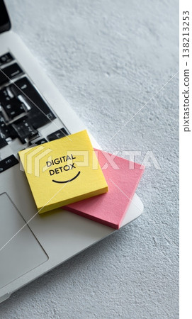 Yellow sticky note displaying digital detox and a smiley face resting on a closed laptop keyboard, promoting disconnection from devices for better work life balance 138213253