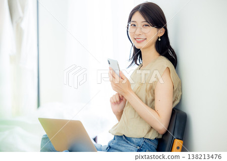A young woman operating a smartphone 138213476