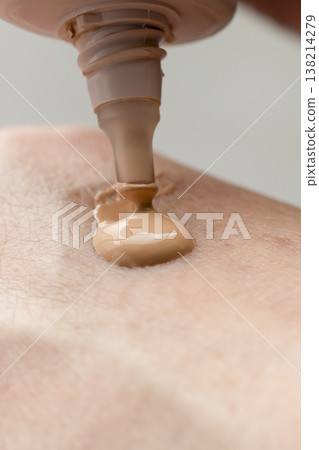 A woman's hands applying makeup; hands applying cream foundation. A woman's hands applying makeup; hands applying cream foundation. 138214279