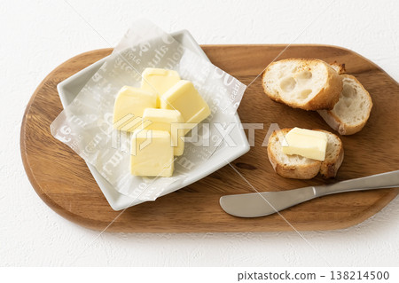 木板上放著切片奶油和法國麵包。 138214500