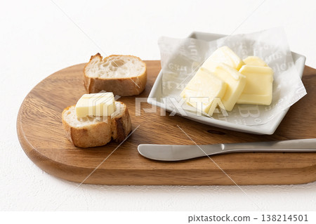 Sliced butter and baguette on a wooden board 138214501