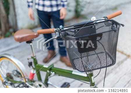 A bicycle with a basket and a person's feet. 138214891