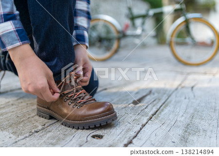 一名男子在戶外繫登山靴。 138214894