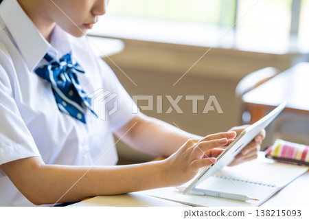 一名女學生在教室裡操作平板電腦時的側臉。 一名女學生在教室裡操作平板電腦時的側臉。 138215093