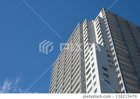 The exterior of a high-rise apartment building against a blue sky; a powerful composition viewed from below. 138215479