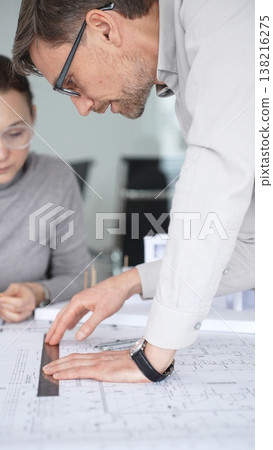 Architects discussing blueprints and a structural model on a desk, focusing on design concepts, project planning, and architectural development during an office meeting, close up Architects discussing blueprints and a structural model on a desk, focusing on design concepts, project planning, and architectural development during an office meeting, close up 138216275