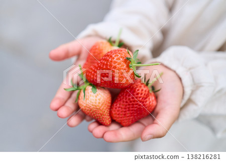 一個孩子手裡拿著草莓 一個孩子手裡拿著草莓 138216281
