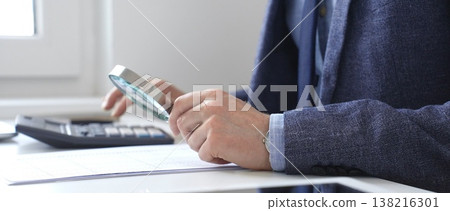 Financial analyst reviewing accounting reports, calculating data with calculator and magnifying glass on corporate workspace. Audit and taxes in business Financial analyst reviewing accounting reports, calculating data with calculator and magnifying glass on corporate workspace. Audit and taxes in business 138216301