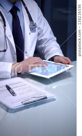 Medical doctor analyzing digital health records on a tablet computer, ensuring patient data management and secure care information in a modern clinic setting 138216336