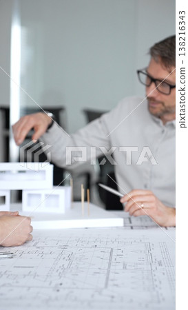 Architects and designer planning a modern house building project, collaborating on construction blueprints and architectural model in a professional office, close up Architects and designer planning a modern house building project, collaborating on construction blueprints and architectural model in a professional office, close up 138216343